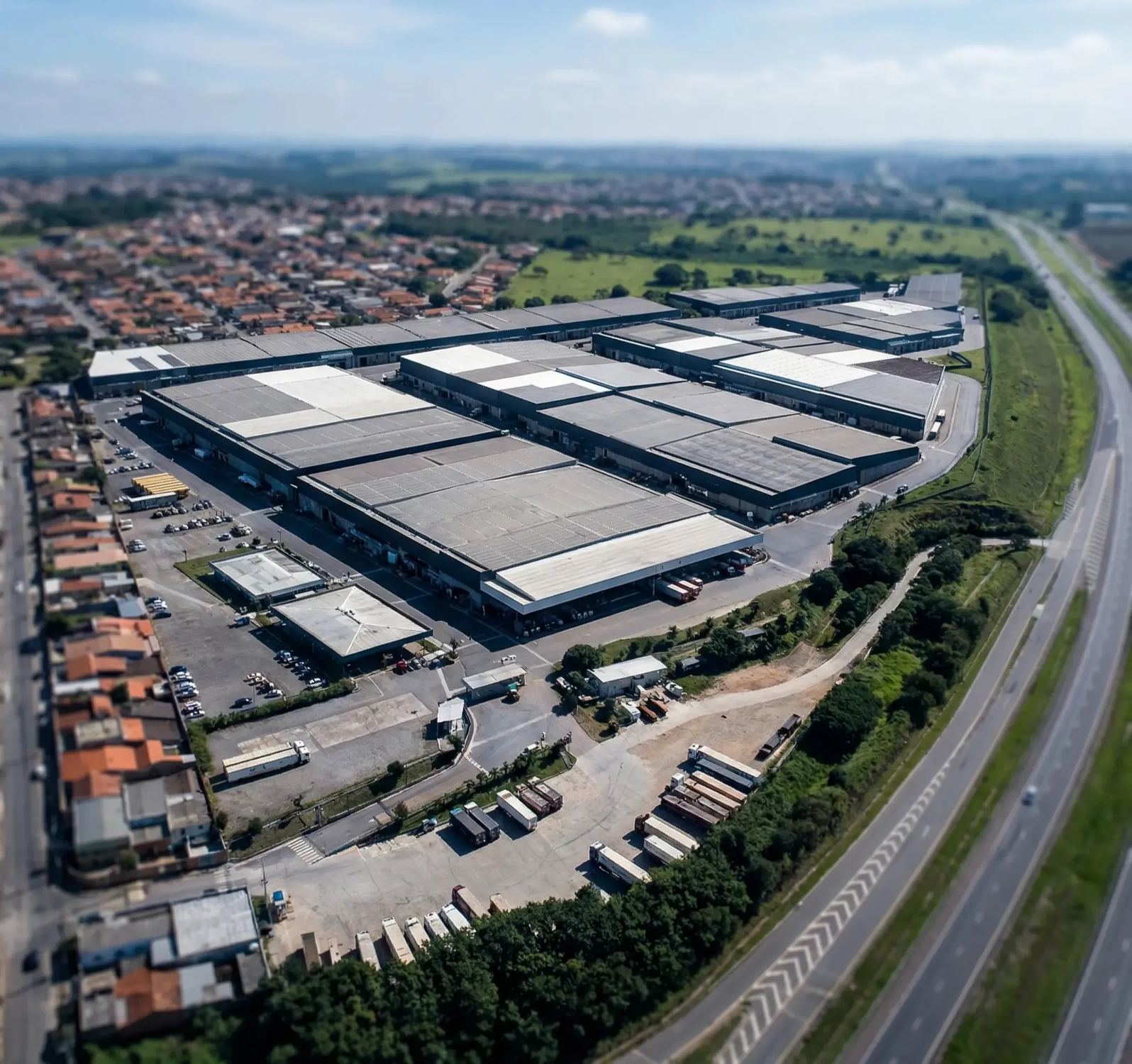 Vista aérea de complexo de galpões industriais com docas, áreas de circulação e acesso rodoviário